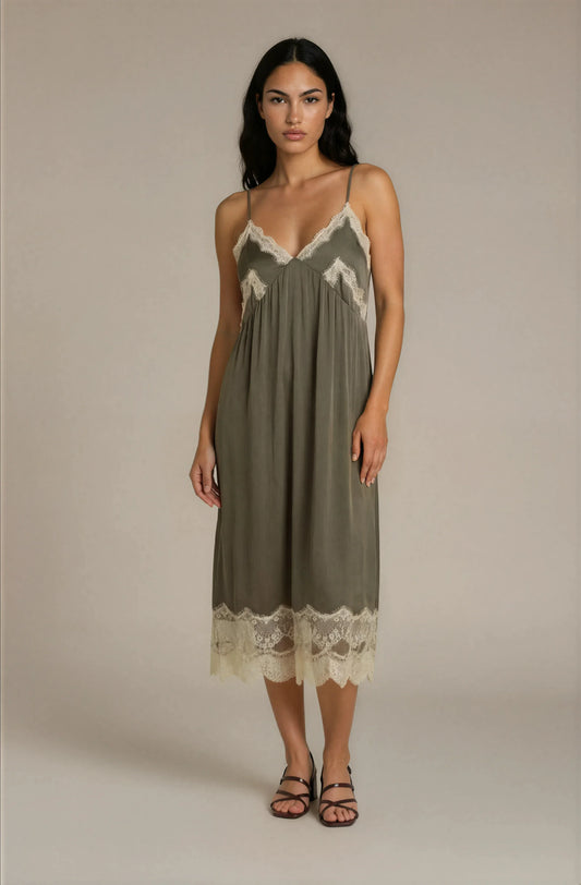 Woman wearing a green slip dress with lace trim on a beige background