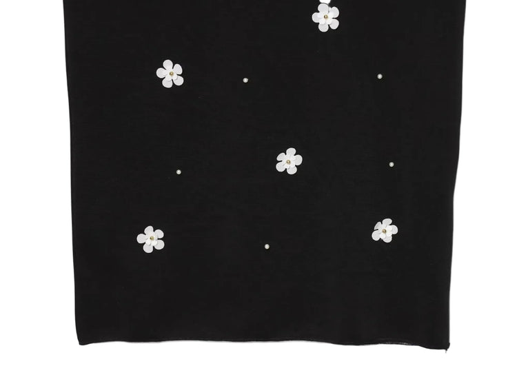 Black women's sleeveless dress with white floral patterns for Spring on a white background close up of bottom of dress