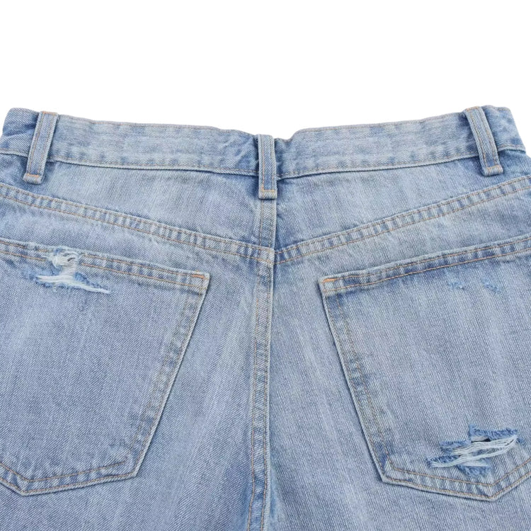 Close-up of a pair of light blue denim jeans with distressed details on a white background
