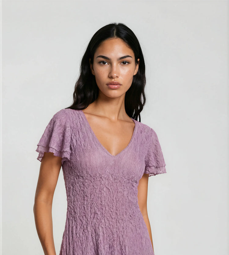Woman wearing a purple dress against a plain background