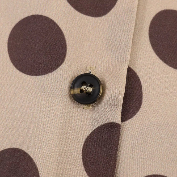 Close-up of a button on fabric with brown polka dots