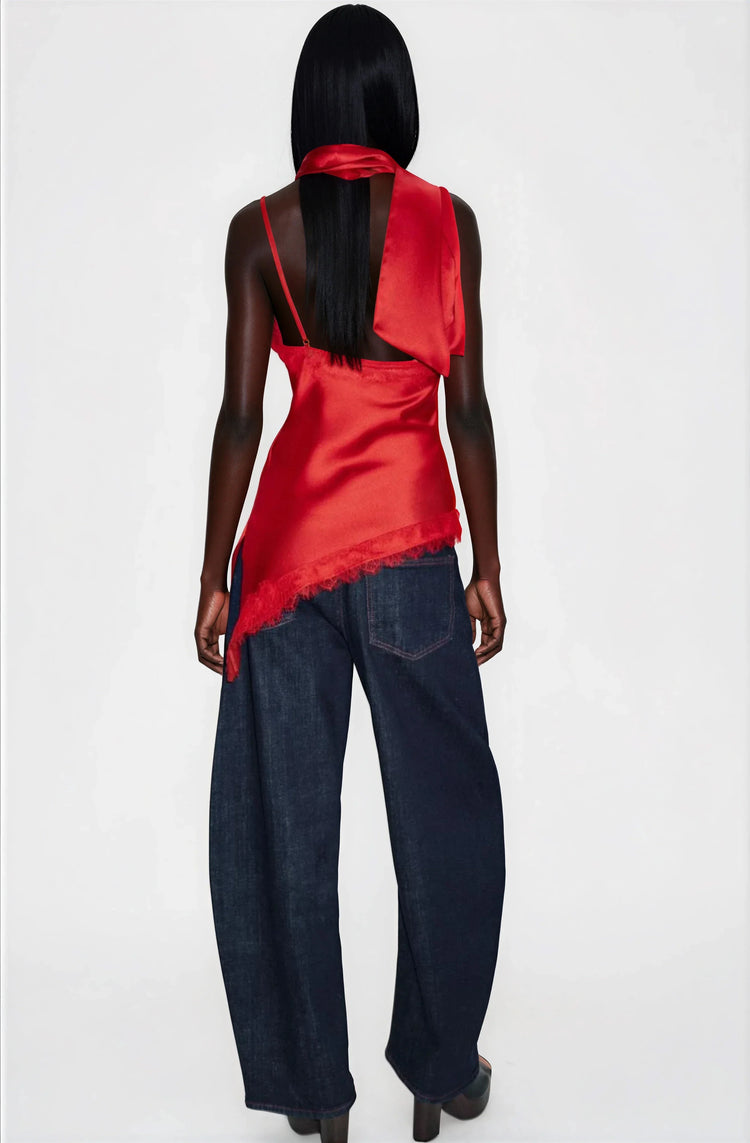 Person wearing a red top and dark blue jeans on a white background