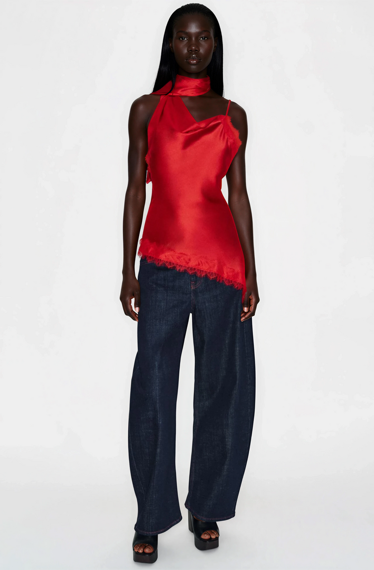 Person wearing a red halter top and dark blue jeans on a white background