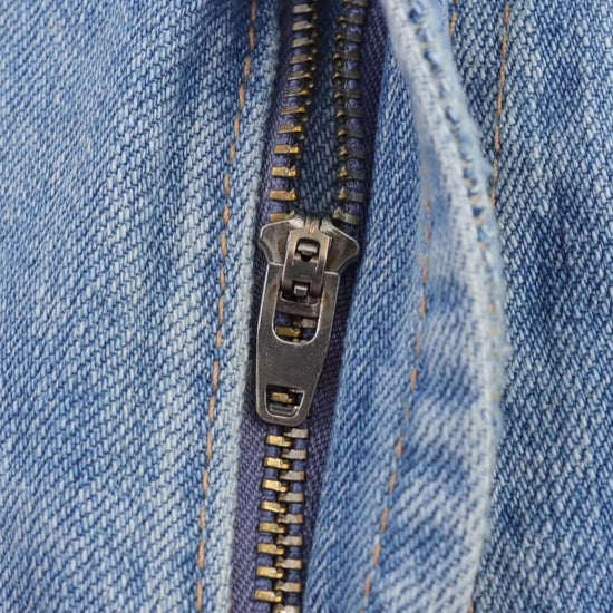 Close-up of a zipper on blue denim fabric