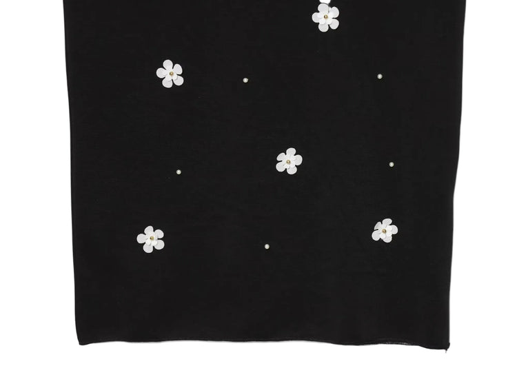 Black women's sleeveless dress with white floral patterns for Spring on a white background close up of bottom of dress
