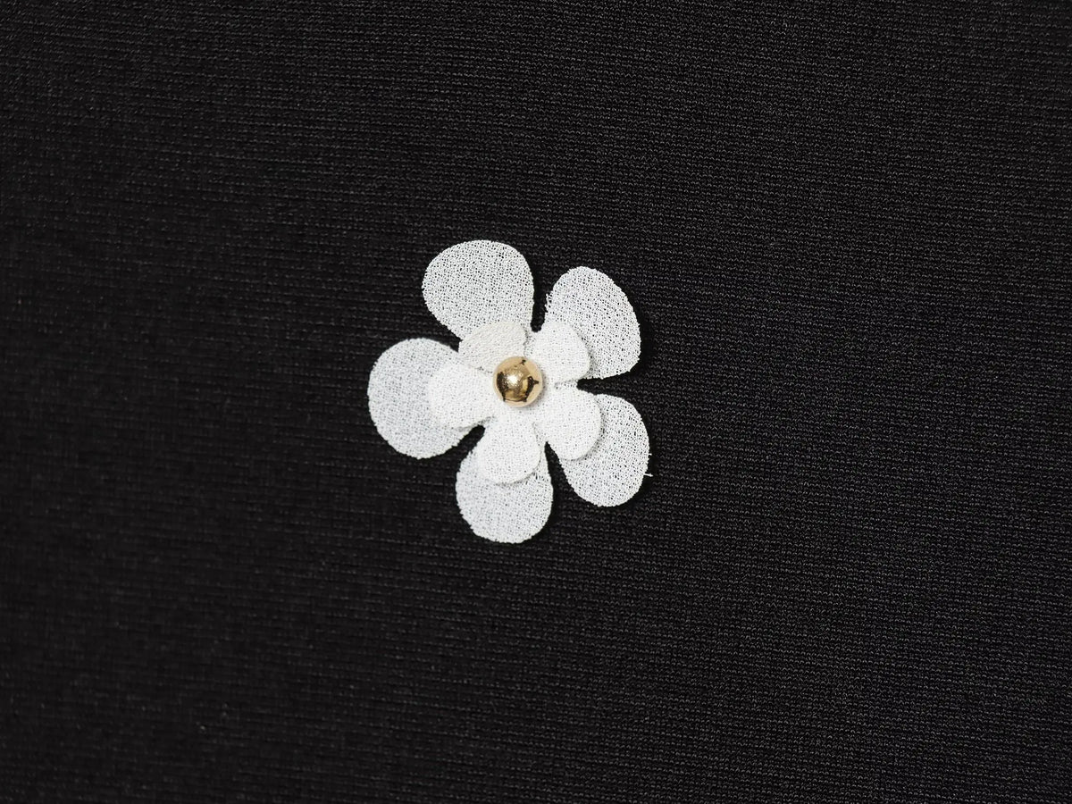 Black women's sleeveless dress with white floral patterns for Spring on a white background close up of fabric and white floral detail
