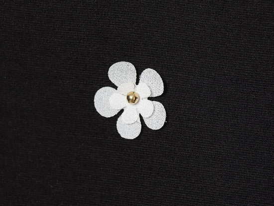 Black women's sleeveless dress with white floral patterns for Spring on a white background close up of fabric and white floral detail