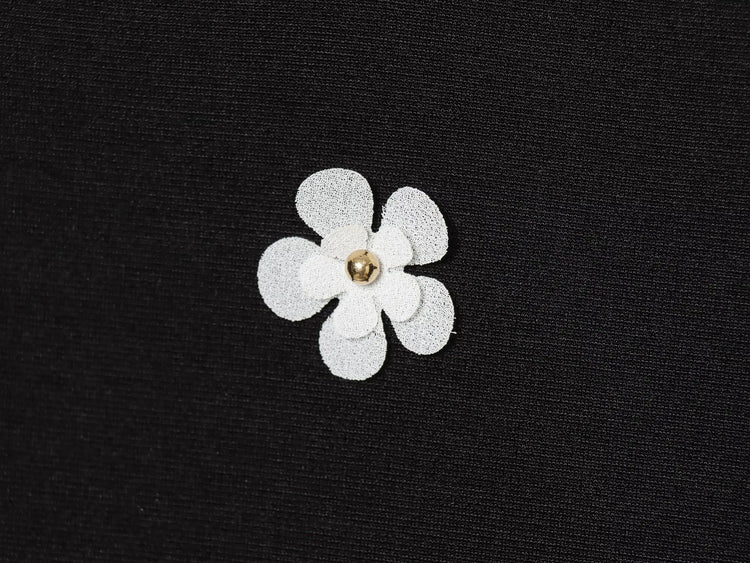 Black women's sleeveless dress with white floral patterns for Spring on a white background close up of fabric and white floral detail