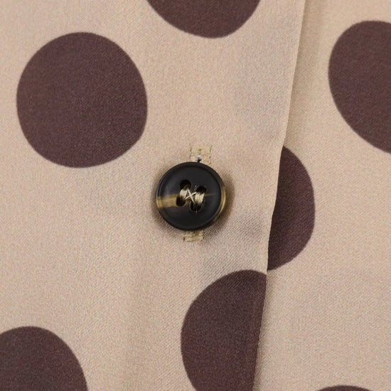 Close-up of a button on fabric with brown polka dots